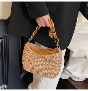 Detail of straw woven bag featuring amber resin chain strap and natural texture