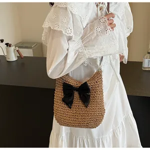 Detail einer handgewebten Strohschultertasche mit schwarzer Schleife und dunklem Gurt