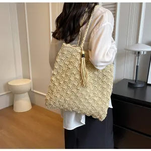 Detailed close-up of handmade hollow straw woven tote with decorative tassel and beads