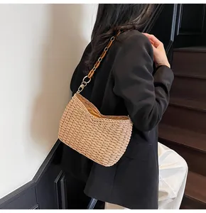 Straw shoulder bag with metal chain and amber acrylic link strap on a female model