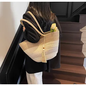 Détail d'un sac cabas tissé en dégradé avec pompon à franges et perles en bois naturel