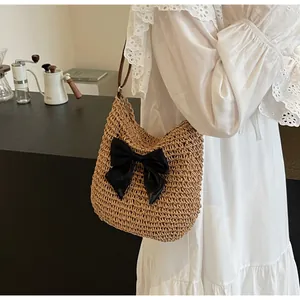 Detail der handgewebten Strohschultertasche mit großer schwarzer Satinschleife und Riemen