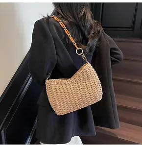 Detail of hand-woven straw bag with amber resin chain strap and metallic gold hardware