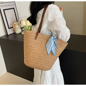 Detail of hand-woven straw bucket bag with brown straps and a blue striped scarf accent