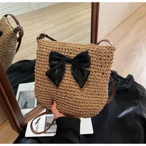 Detail der handgewebten Strohtasche mit großer schwarzer Schleife und Lederriemen