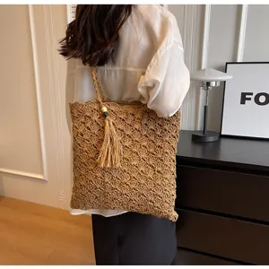 Detail of the woven straw handbag featuring hollow petal patterns and a tassel with wood beads