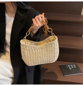 Detail of hand-woven straw bag featuring amber resin chain strap and gold hardware
