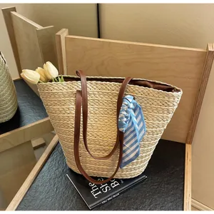 Detail of straw woven bucket bag with brown leather straps and striped silk scarf