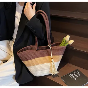 Détail d'un grand sac cabas tissé avec design tricolore et glands en perles de bois