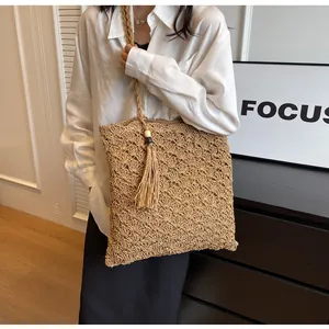 Detail of the woven straw tote bag featuring wavy crochet patterns and wooden bead tassel