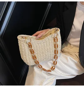 Straw bag with amber resin chain and golden rings on black blazer background