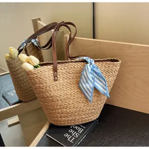 Detailed straw woven bucket bag with brown leather handles and a blue striped silk scarf