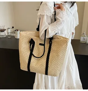 Détail de grand sac cabas en paille avec texture tressée et anses en corde noire