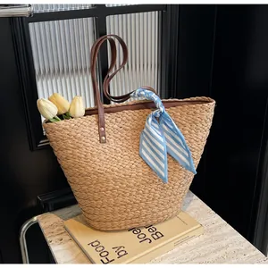 Detail of woven straw tote bag with brown handles, striped scarf, and tulip decorations