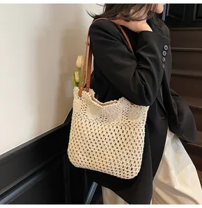 Detail of hollow woven tote bag with brown leather handles held by model in black suit