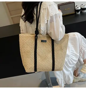 Gros plan détaillé d'un grand sac cabas en paille avec des anses noires en corde tressée