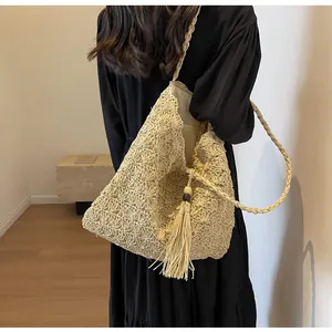 Close-up of crochet hollow pattern and tassel detail on the beige straw beach tote