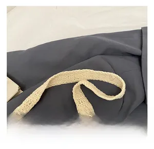 Detail showing the comfortable hand-woven cotton strap and texture of the beige beach bag