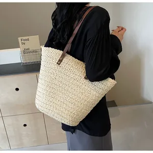 Detail of hand-woven straw bucket bag with dark brown leather straps and rivet accents