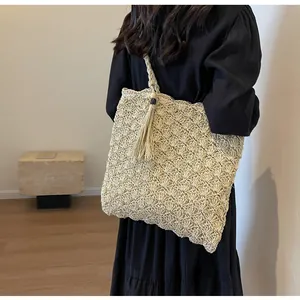 Detail of hand-woven straw bag featuring shell pattern texture and elegant long tassel charm