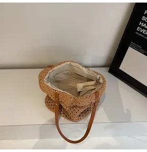 Detail of woven straw tote bag featuring brown hollow knit and fabric lining