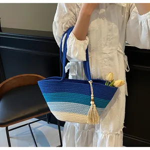Détail du grand sac de plage tissé avec rayures bleues et accessoire de pompon crème