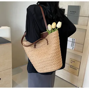 Detail of straw woven tote bag with brown leather handles and spacious interior capacity