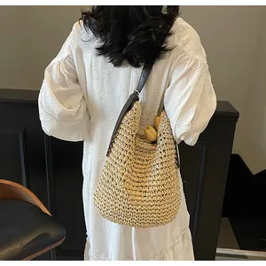 Stro hobo tas met lederen riem getoond op model in een witte jurk met pofmouwen
