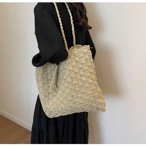 Detail of hollow woven texture and long tassel charm on a summer straw tote bag