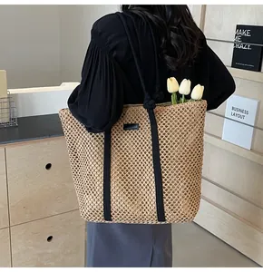 Détail du sac cabas en paille tissée creuse avec poignées en corde et écusson en cuir noir