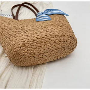 Detail of woven straw tote bag with chunky texture and silk scarf handle accent