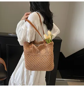 Detail of hollow woven straw tote bag with round floral patterns and leather handles