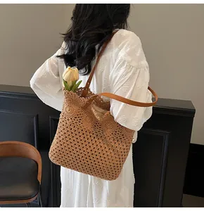 Detail of hollow woven brown tote bag with leather straps and floral crochet patterns