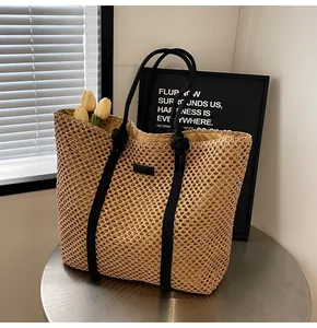 Détail du sac cabas en paille tissée avec poignées en corde noire sur une table en métal