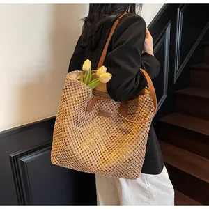 Détail d'un grand sac cabas en paille avec lanières en cuir marron porté par un mannequin