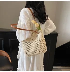 Detail of hand-woven crochet tote bag with hollow floral pattern and leather shoulder strap