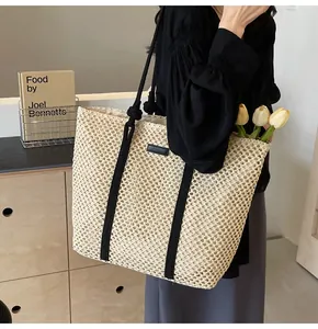 Détail d'un cabas en paille avec poignées en corde noire et écusson en cuir