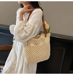 Detail of hollow-out woven tote bag with brown leather straps and floral lace trim