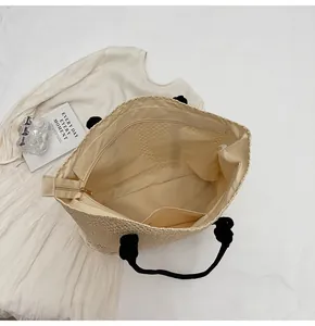 Vue intérieure du sac cabas en paille montrant le compartiment spacieux et les poches