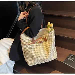 Détail du grand sac cabas en paille avec lanières en cuir marron et tissage en losange