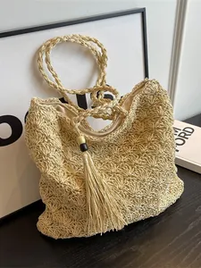 Handmade woven straw beach bag with hollow pattern, wooden bead tassel, and zipper closure