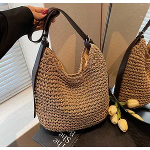 Detail van handgeweven strooien hobo-tas met bruine lederen riem en stoffen voering