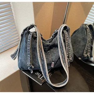 Détail d'un sac bandoulière en jean délavé avec fermeture à cordon et étiquette