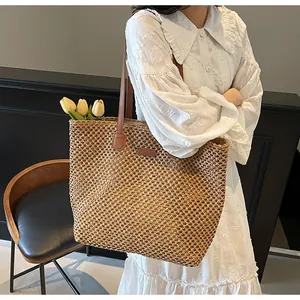 Détail d'un sac cabas en paille tissée avec anses en cuir sur robe d'été blanche