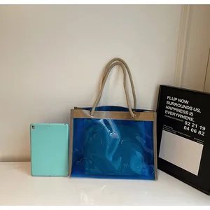 Detail of transparent PVC tote bag with rustic hemp rope handles and blue inner pouch