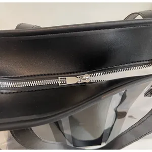 Close-up of silver metal zipper and stitching on black PVC tote bag for women
