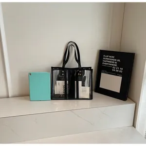 Detail view of large transparent PVC tote bag with black leather straps and tablet