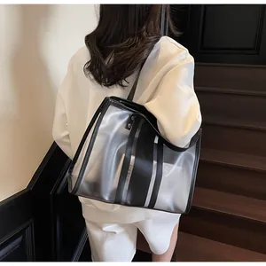 Detail of transparent PVC tote bag with black stripes and leather straps shown on shoulder