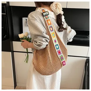 Detail of crochet knit shoulder bag with colorful floral embroidery on wide strap