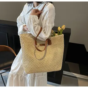 Détail du sac cabas en paille tissée avec anses en cuir et tulipes jaunes à l'intérieur